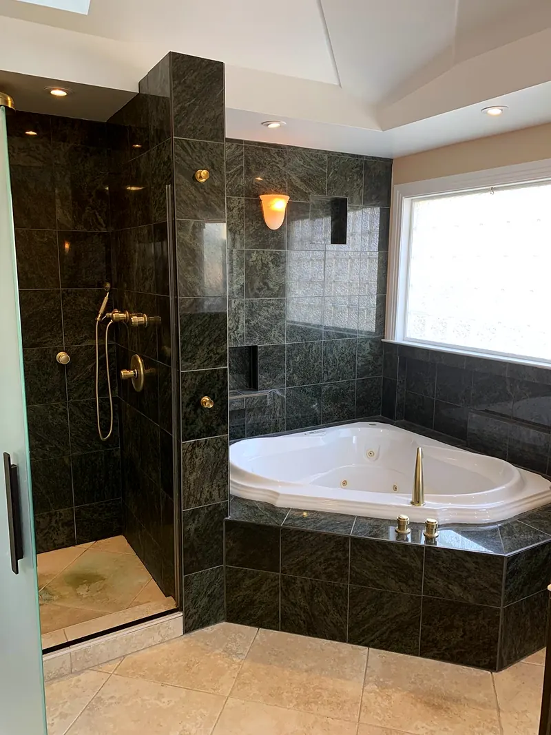 Master bathroom with green marble wall tile, a corner jetted tub and a glass walk-in shower