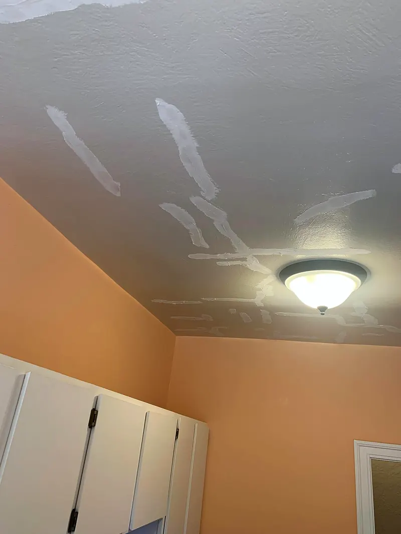 Bedroom ceiling with a network of cracks covered in joint compound, light fixture in the middle