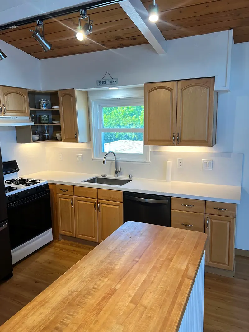 Kitchen with a butcher block island, white quartz counters, wood cabinets and a tongue-and-groove wood ceiling