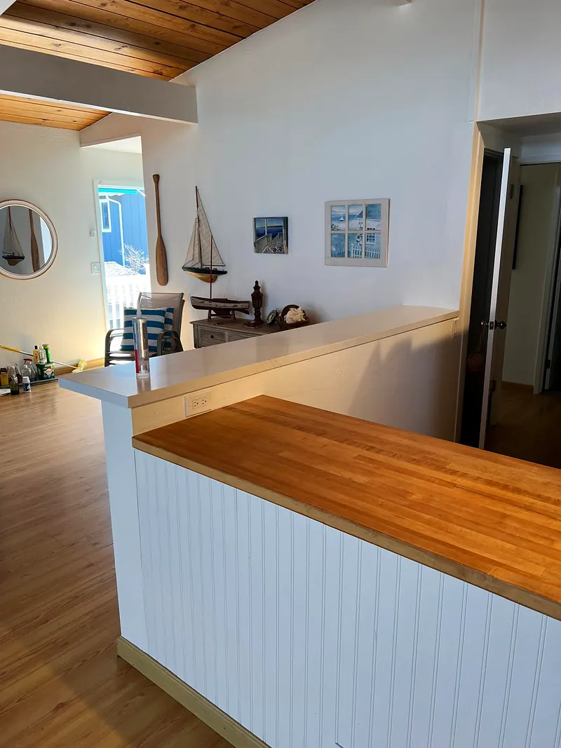 Kitchen peninsula with a butcher block top and white beadboard panel facing the living room