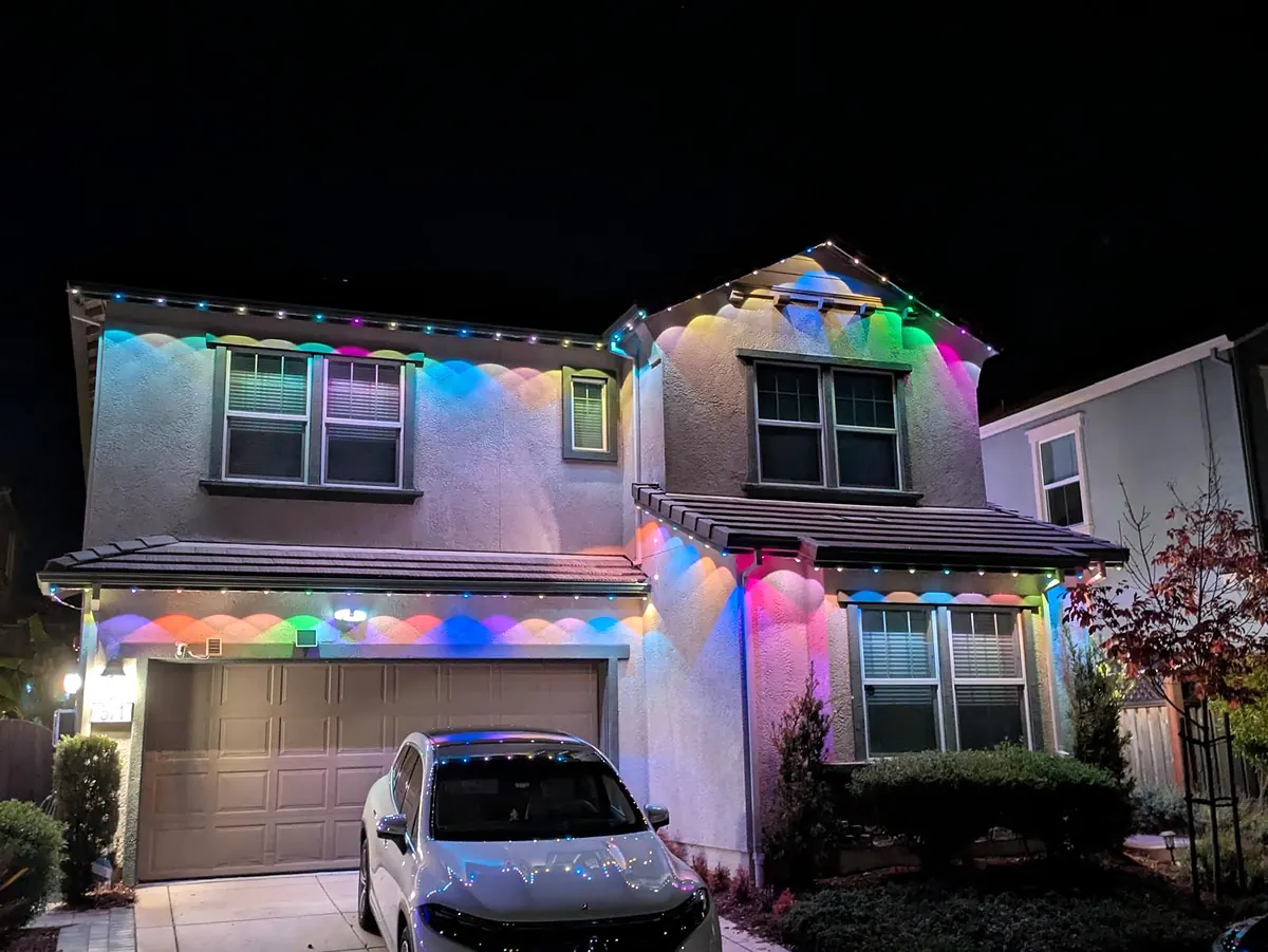 Close view of color lights spaced evenly under the eaves of a two story house