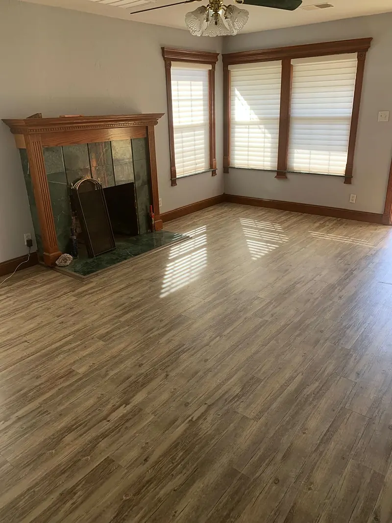 Living room with a tiled fireplace, wood-trimmed windows and new wood-look plank floor
