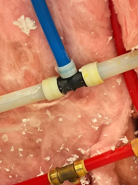 New PEX supply lines with brass and plastic fittings in an open wall