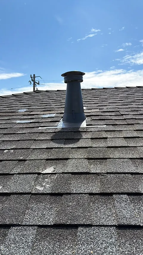 Finished vent flashing on a shingle roof under a clear sky
